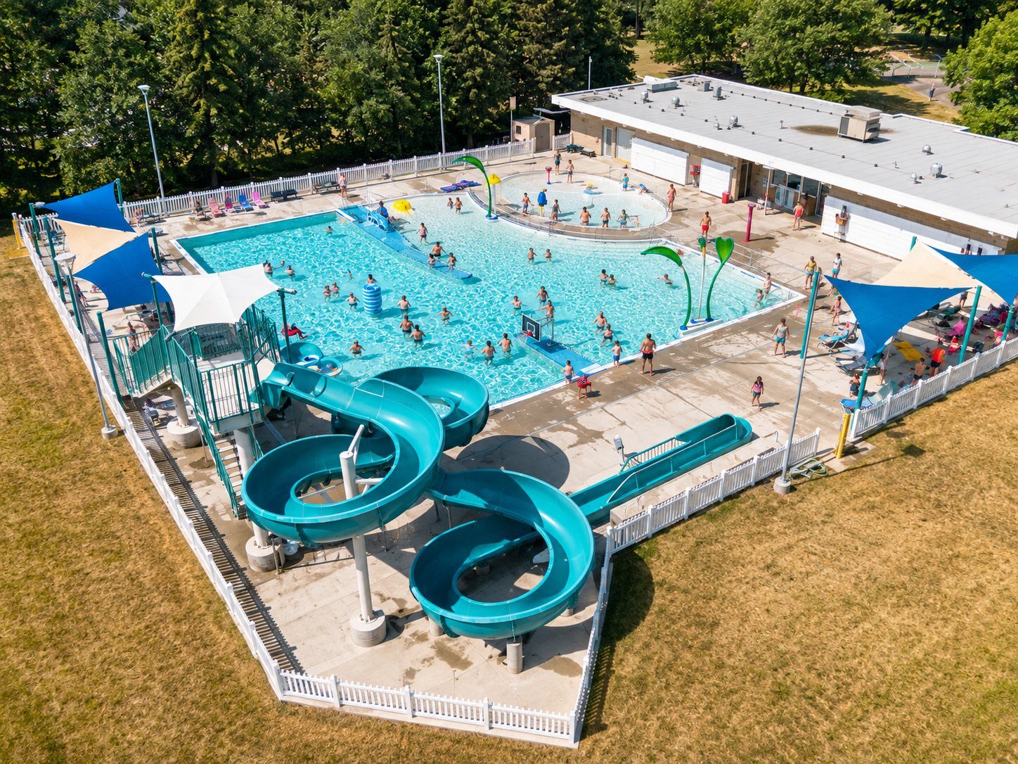An outdoor swimming pool with a waterslide on a summer afternoon